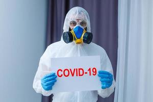 hombre vistiendo químico protector traje en ligero gris antecedentes. coronavirus brote foto