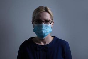 un atractivo joven mujer usa un papel cara máscara a proteger sí misma desde el h1n1 virus, aislado en blanco, con habitación para tu texto foto