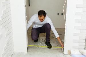 young builder with yellow tape measure on real construction site, selective focus , natural soft light photo