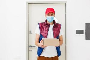 Delivery man holding paper bag with food on white background, food delivery man in protective mask photo