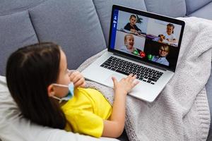 little girl in a protective mask at distance home schooling, quarantine photo