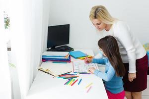 mother and daughter in protective mask do homework at distance home schooling, quarantine photo