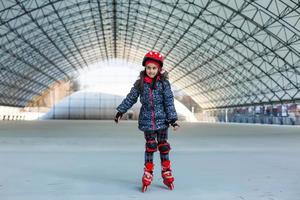 pequeño linda contento niña patinar en un grande hangar foto