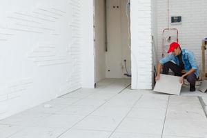 Floor tile installation, worker in a white office room photo