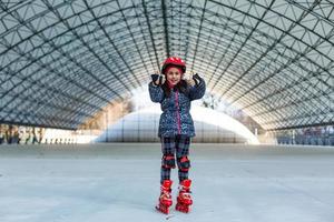 little cute happy girl rollerblading in a big hangar photo