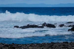 grande olas estrellarse en contra el rocas en el Oceano foto