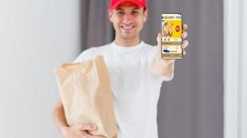 Paper pocket and food containers in hands of a smiling deliveryman. Quality service of a restaurant. photo