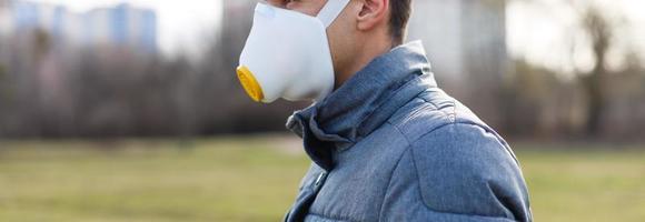 Asian man wearing the face mask due to air pollution - Young adult on park with Pollution mask - person protecting from air contamination or coronavirus or covid-19 by wearing mask. photo