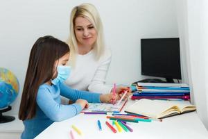 mother and daughter in protective mask do homework at distance home schooling, quarantine photo