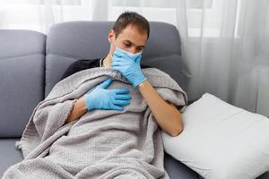 Hands with blue gloves putting on a medical face mask to protect the upper respiratory tract. Man hand puts on a protective facial mask against virus and infection diseases. Coronavirus 2019-nCoV photo