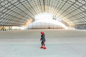 little cute happy girl rollerblading in a big hangar photo