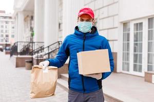 Courier in protective mask and medical gloves delivers takeaway food. Delivery service under quarantine, disease outbreak, coronavirus covid-19 pandemic conditions. photo