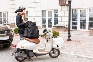 masked woman delivering food on a motorcycle photo