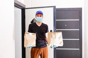 the courier delivers the parcel to the door, in latex gloves, contactless delivery during the quarantine period photo