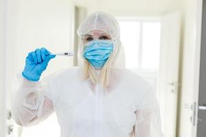 Researcher in hazmat protective suit examining a test tube in the chemical lab. photo