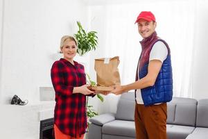 Man food delivery holding paper bag in an apartment photo