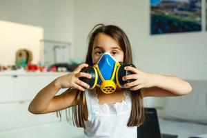 Close-up view of little girl in a big protective mask against viruses covid-19 and dust in the air. photo