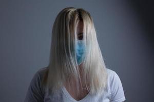un atractivo joven mujer usa un papel cara máscara a proteger sí misma desde el h1n1 virus, aislado, con habitación para tu texto foto