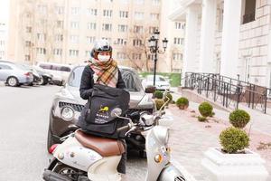 enmascarado mujer entregando comida en un motocicleta foto