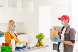 Young Caucasian couple in protective masks doing shoppings at home, quarantine photo