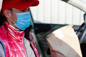 delivery by car. man in protective mask and medical gloves holding a paper box. Delivery service under quarantine, disease outbreak, coronavirus covid-19 pandemic conditions. photo