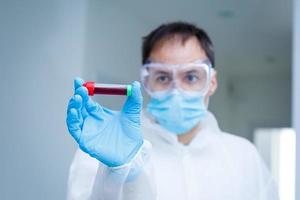 coronavirus covid 19 infected blood sample in sample tube in hand of scientist with biohazard protection clothing in coronavirus covid 19 reseach laboratory, coronavirus covid-19 vaccine research photo