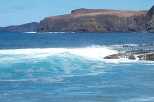 grande olas estrellarse en contra el rocas en el Oceano foto