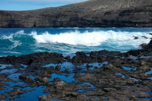 grande olas estrellarse en contra el rocas en el Oceano foto