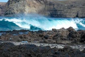 grande olas estrellarse en contra el rocas en el Oceano foto