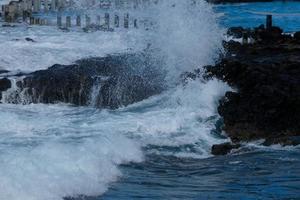 grande olas estrellarse en contra el rocas en el Oceano foto