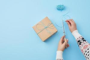 gift wrapped and tied with a brown rope, female hand with scissors cuts a brown rope photo