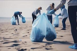a group of unrecognizable people collecting garbage from the beach in blue bags for the problem of plastic pollution in the environment photo