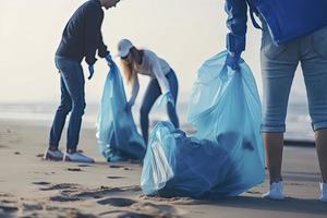 a group of unrecognizable people collecting garbage from the beach in blue bags for the problem of plastic pollution in the environment photo