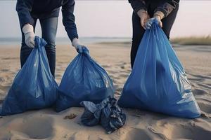 a group of unrecognizable people collecting garbage from the beach in blue bags for the problem of plastic pollution in the environment photo