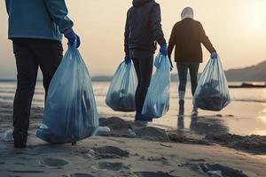 a group of unrecognizable people collecting garbage from the beach in blue bags for the problem of plastic pollution in the environment photo