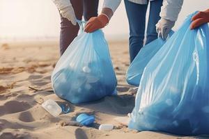 a group of unrecognizable people collecting garbage from the beach in blue bags for the problem of plastic pollution in the environment photo