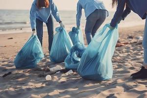 a group of unrecognizable people collecting garbage from the beach in blue bags for the problem of plastic pollution in the environment photo