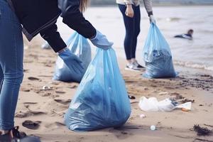 a group of unrecognizable people collecting garbage from the beach in blue bags for the problem of plastic pollution in the environment photo