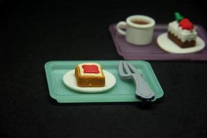 Sweet sugary food shaped eraser. School or office stationary tool supplies with Bread loaf slice, strawberry jam, steel fork shape. isolated photo on dark black background.