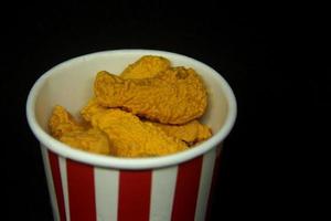 un manojo de sabroso frito pollo conformado borrador. colegio o oficina estacionario herramienta suministros con crujiente insalubre basura comida forma . aislado foto en oscuro negro antecedentes.