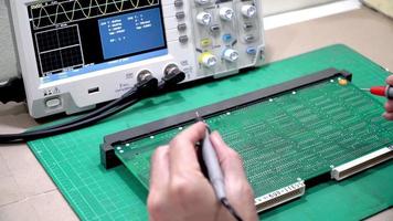 technician is inspecting the circuit board by digital storage oscilloscope video