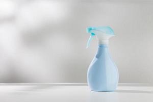 Blue spray bottle on white wooden table. photo