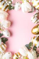 Easter golden eggs and white tulips on pink  background. photo