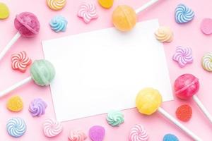 Sweet lollipops and candies and blank greeting card on pink background photo