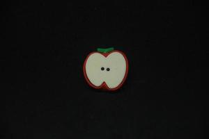 rojo y blanco manzana Fruta conformado borrador estacionario herramientas para oficina o colegio suministros. aislado foto en llanura oscuro negro antecedentes.