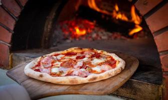 Chef placing pizza in brick oven photo