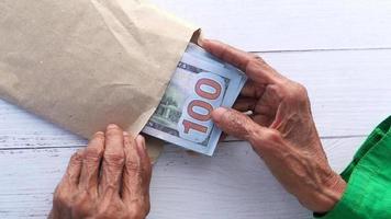 persoon hand- zetten 100 dollar ons dollar contant geld in een envelop video