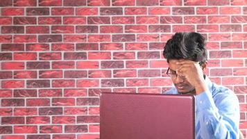 Thoughtful young man using laptop indoor video