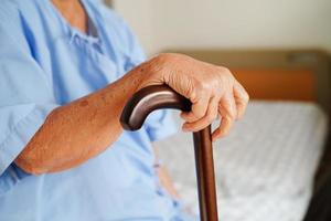 Asian elderly disability woman patient holding walking stick in wrinkled hand at hospital. photo