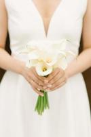 White bridal bouquet of calla lilies in the hands of the bride photo